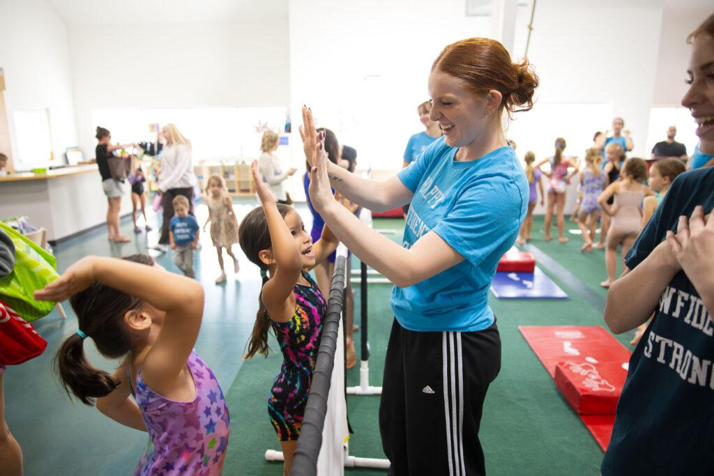 Gymnastics teacher giving a high five to students.